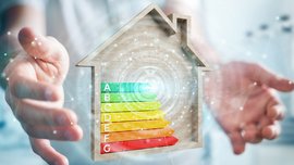 Energieeffizienz im Fokus: Ein Haus mit Bewertungsskala Zwei Hände die ein Energieeffizienzklasse mit einem Haus umrandet halten